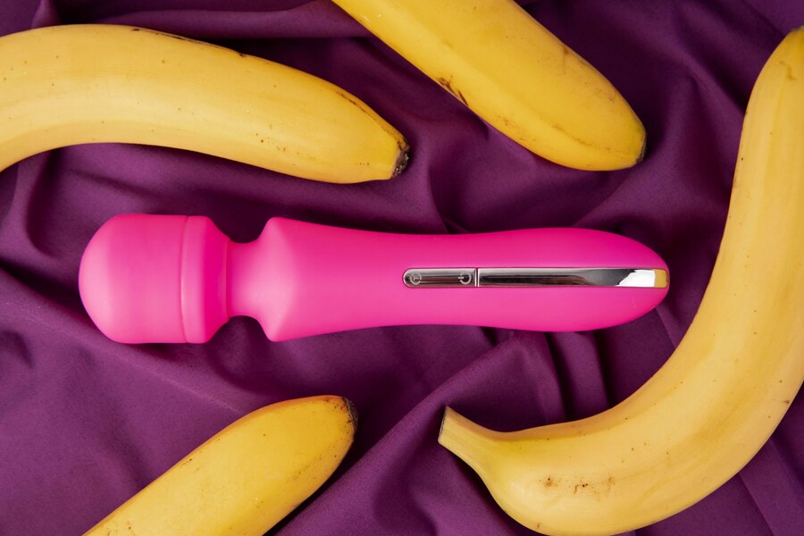 vibratore rosa in mezzo a 4 banane nel letto viola